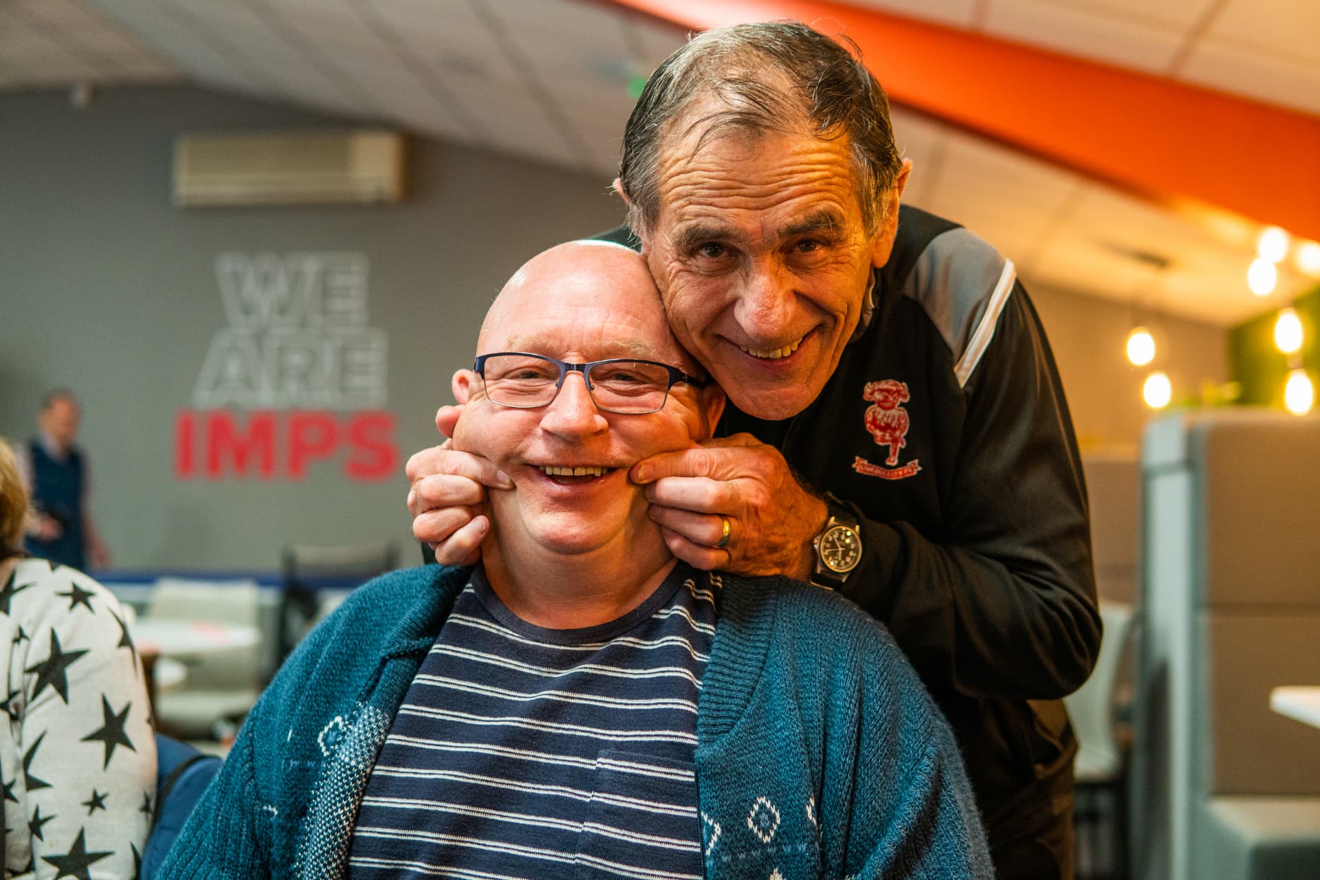 Two friends smiling together at a community gathering